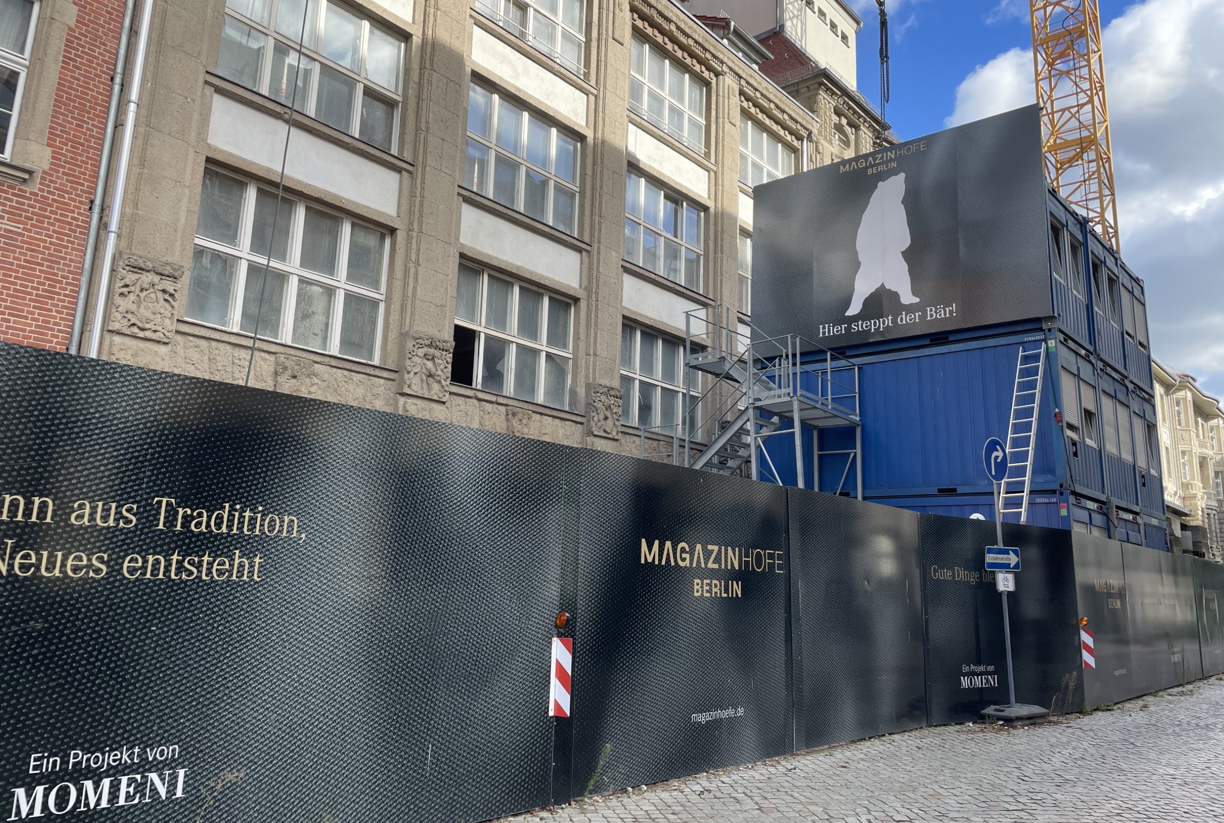 "Bauzaunwerbung für ""MAGAZINHOEFE BERLIN"" mit Slogan ""Hier steppt der Bär!"" und Bärensilhouette, zeigt kreatives Baustellenmarketing."
