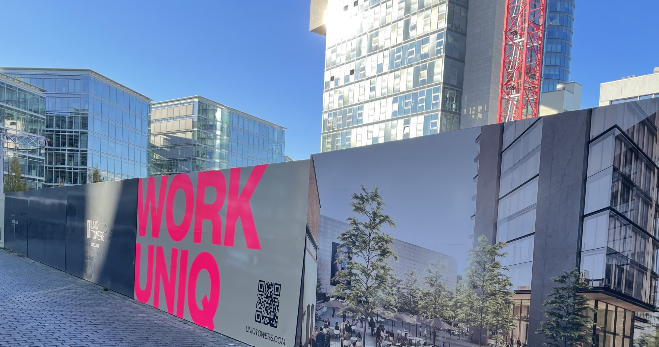 Großflächiges Baustellenplakat mit 'WORK UNIQ' Schriftzug und QR-Code, Beispiel für effektives Baustellenmarketing von Rick Werbewelt.