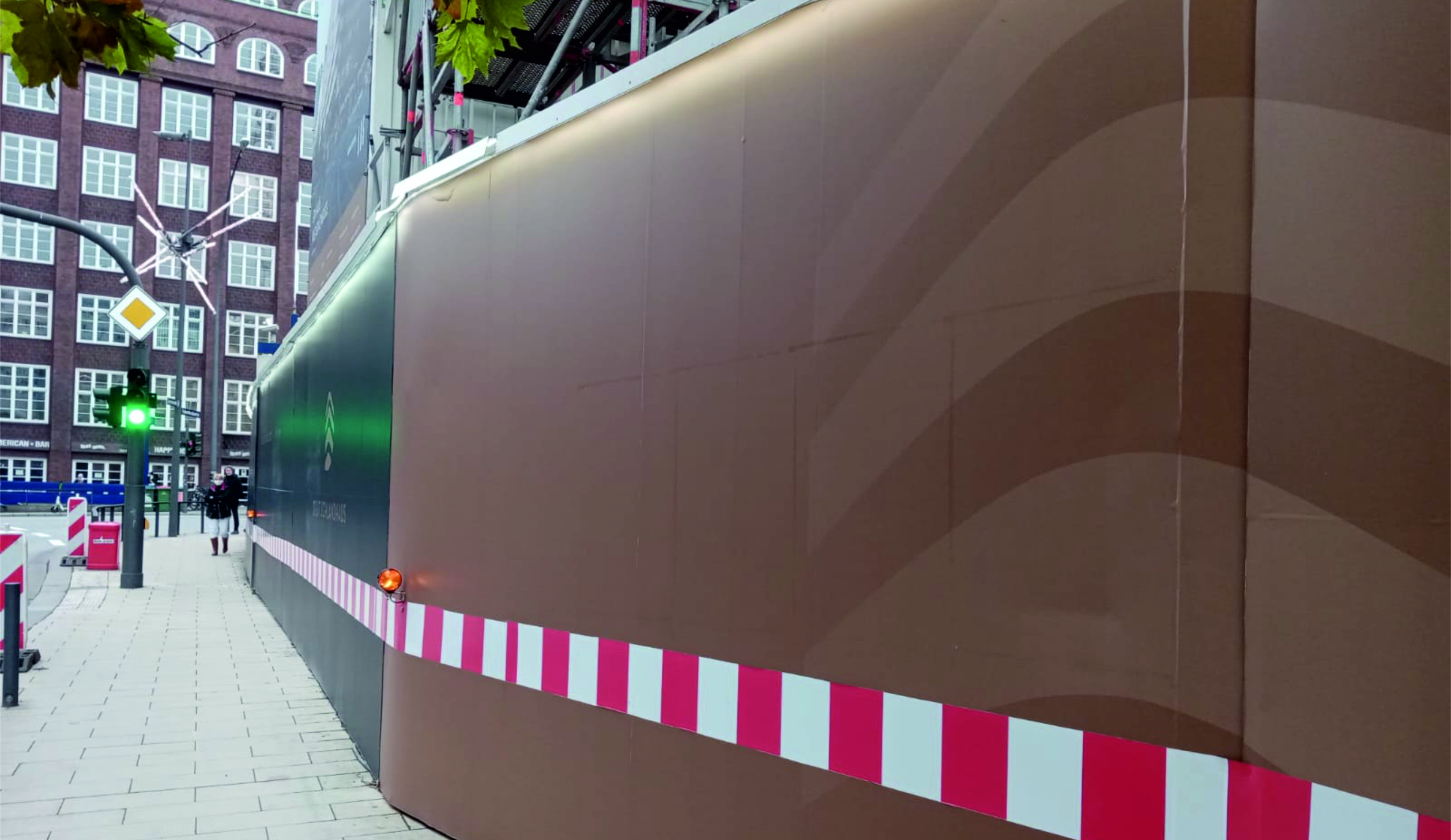 "Bauzaunwerbung für ""MAGAZINHOEFE BERLIN"" mit Slogan ""Hier steppt der Bär!"" und Bärensilhouette, zeigt kreatives Baustellenmarketing."