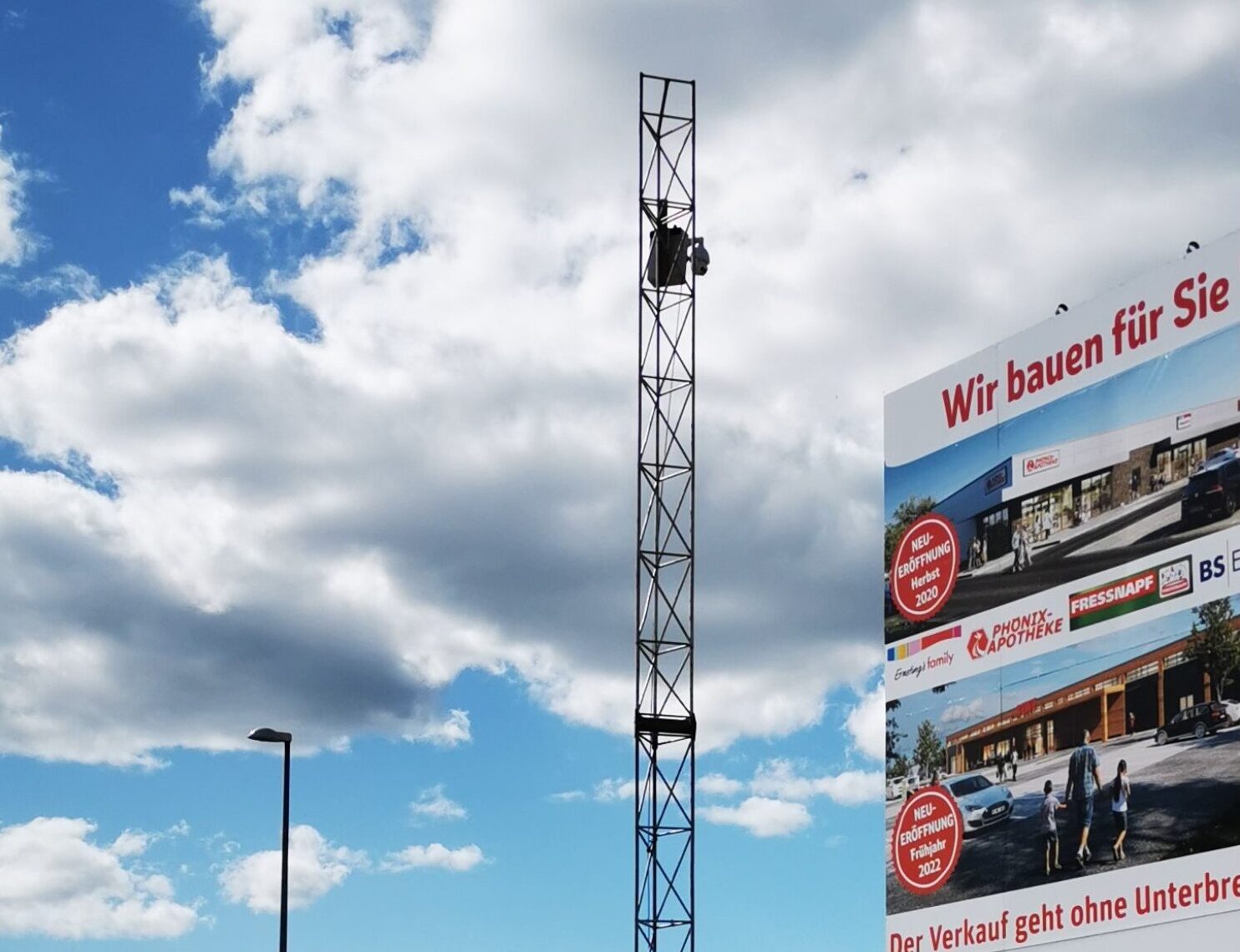 "Hoher Bauzaun mit ""MAGAZINHOEFE BERLIN"" Schriftzug und Website, im Hintergrund ein Kran und Gebäude, zeigt Baustellenmarketing."